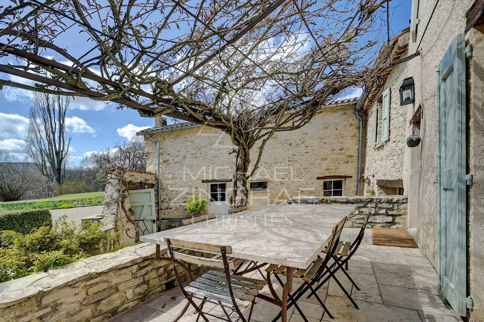 Terrace of a renovated mill with table and chairs, surrounded by greenery in Forcalquier.
