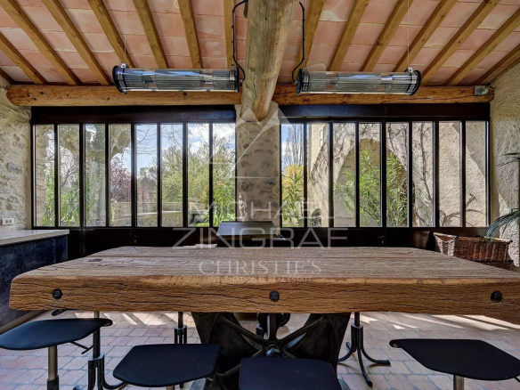 Interior of a renovated mill with a large wooden table and windows overlooking greenery.
