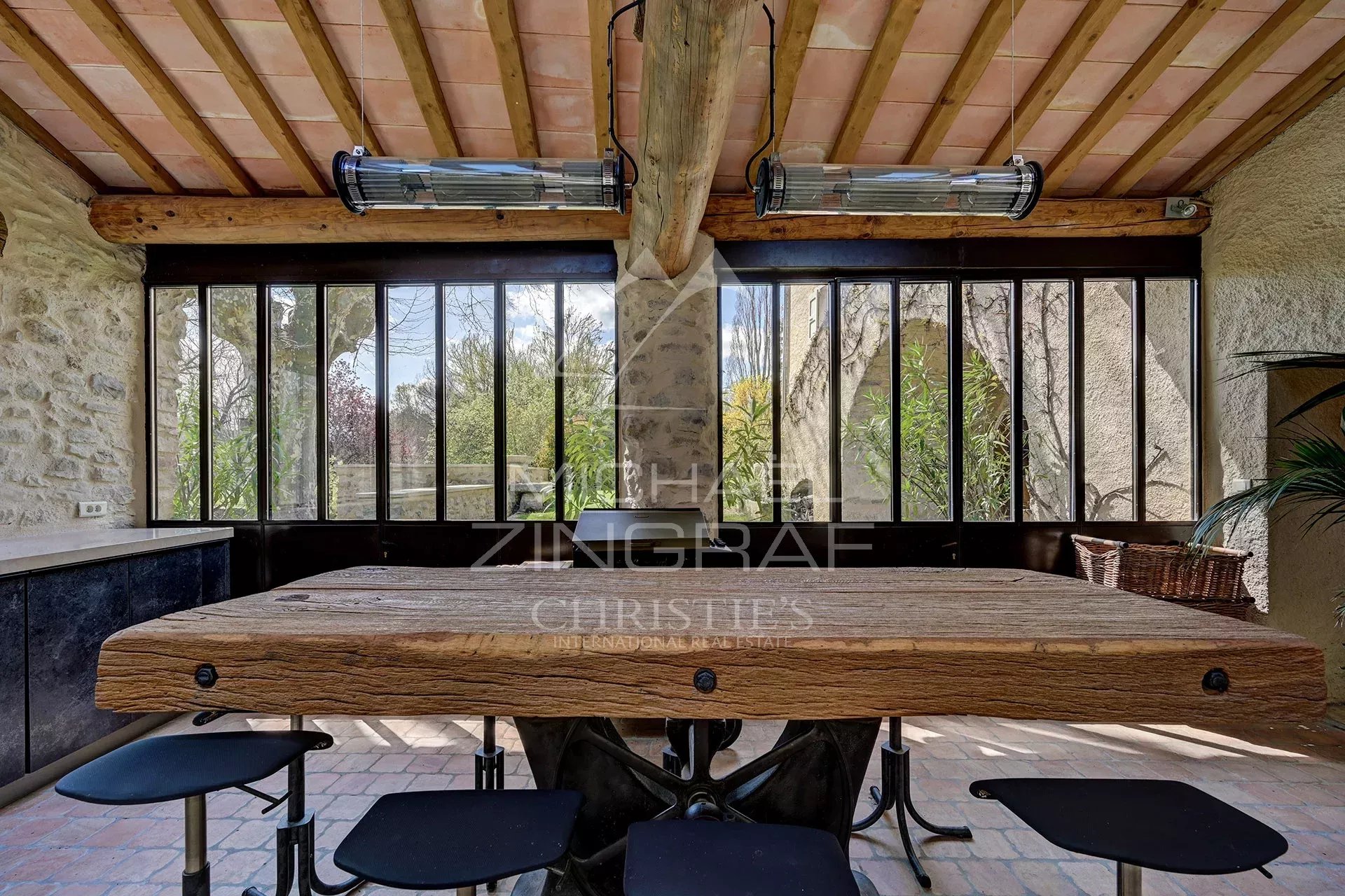 Interior of a renovated mill with a large wooden table and windows overlooking greenery.
