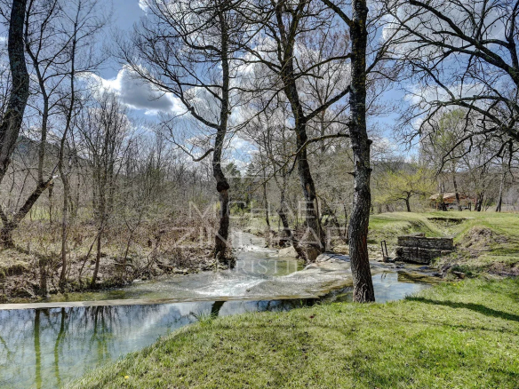 A renovated 17th-century mill on the banks of two streams in a green landscape in Forcalquier.