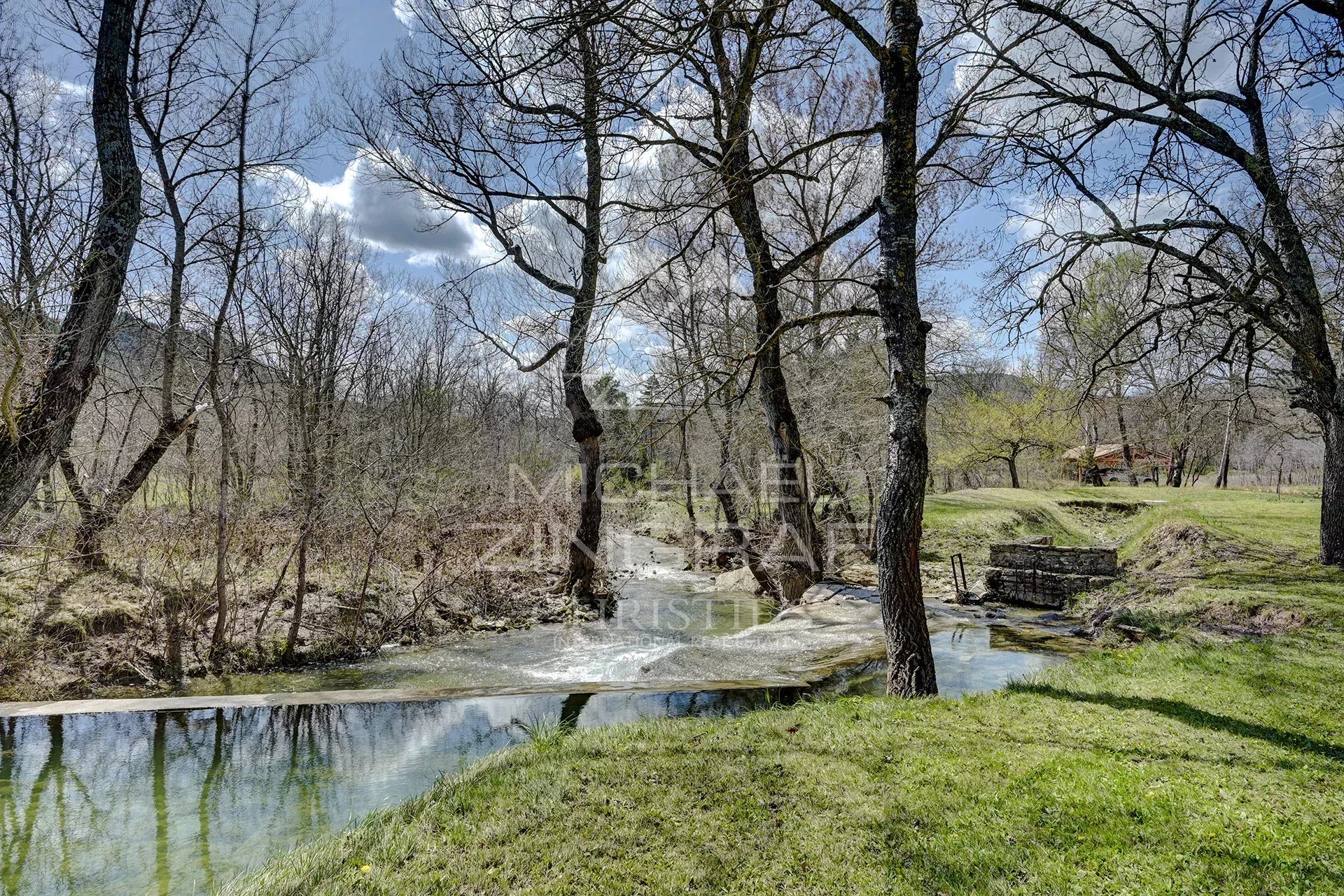 A renovated 17th-century mill on the banks of two streams in a green landscape in Forcalquier.
