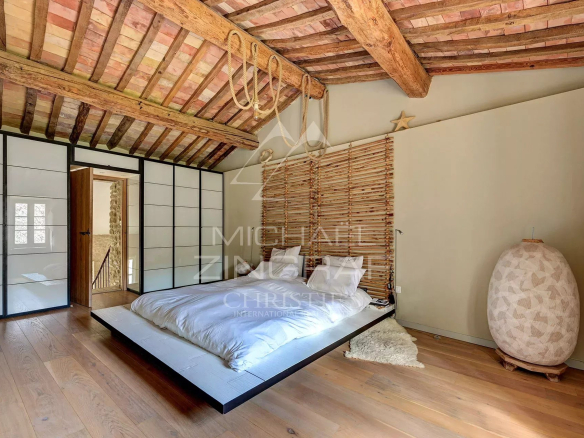 Room in a renovated mill with a wooden ceiling and a modern bed.