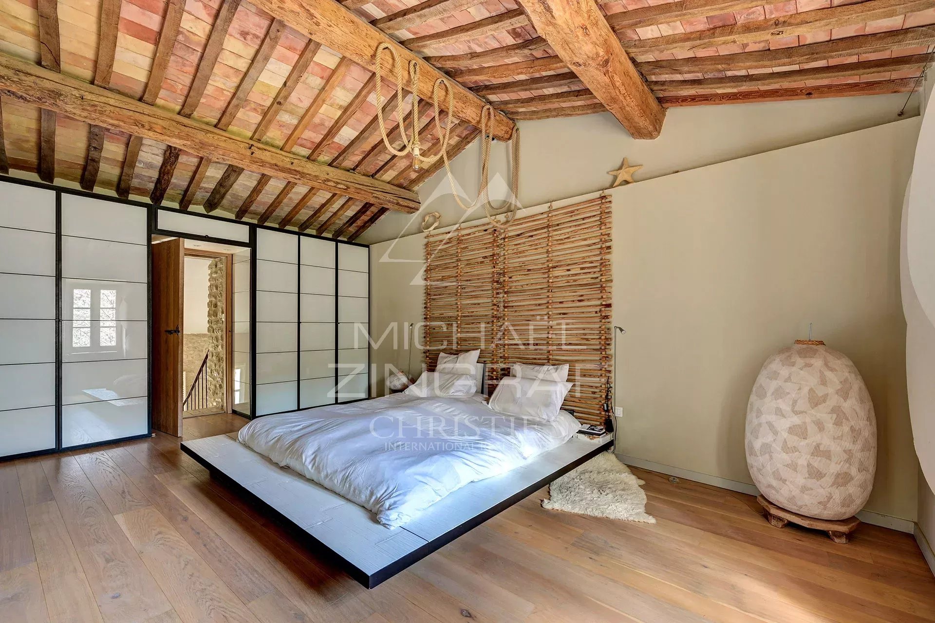 Room in a renovated mill with a wooden ceiling and a modern bed.