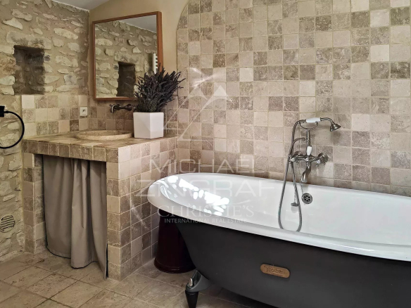 Bathroom in a renovated mill with freestanding bathtub and stone walls.