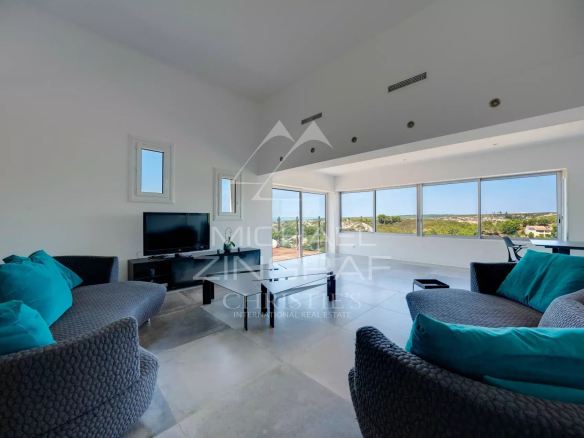 Intérieur d'une villa moderne avec vue sur la mer, salon lumineux et mobilier contemporain.