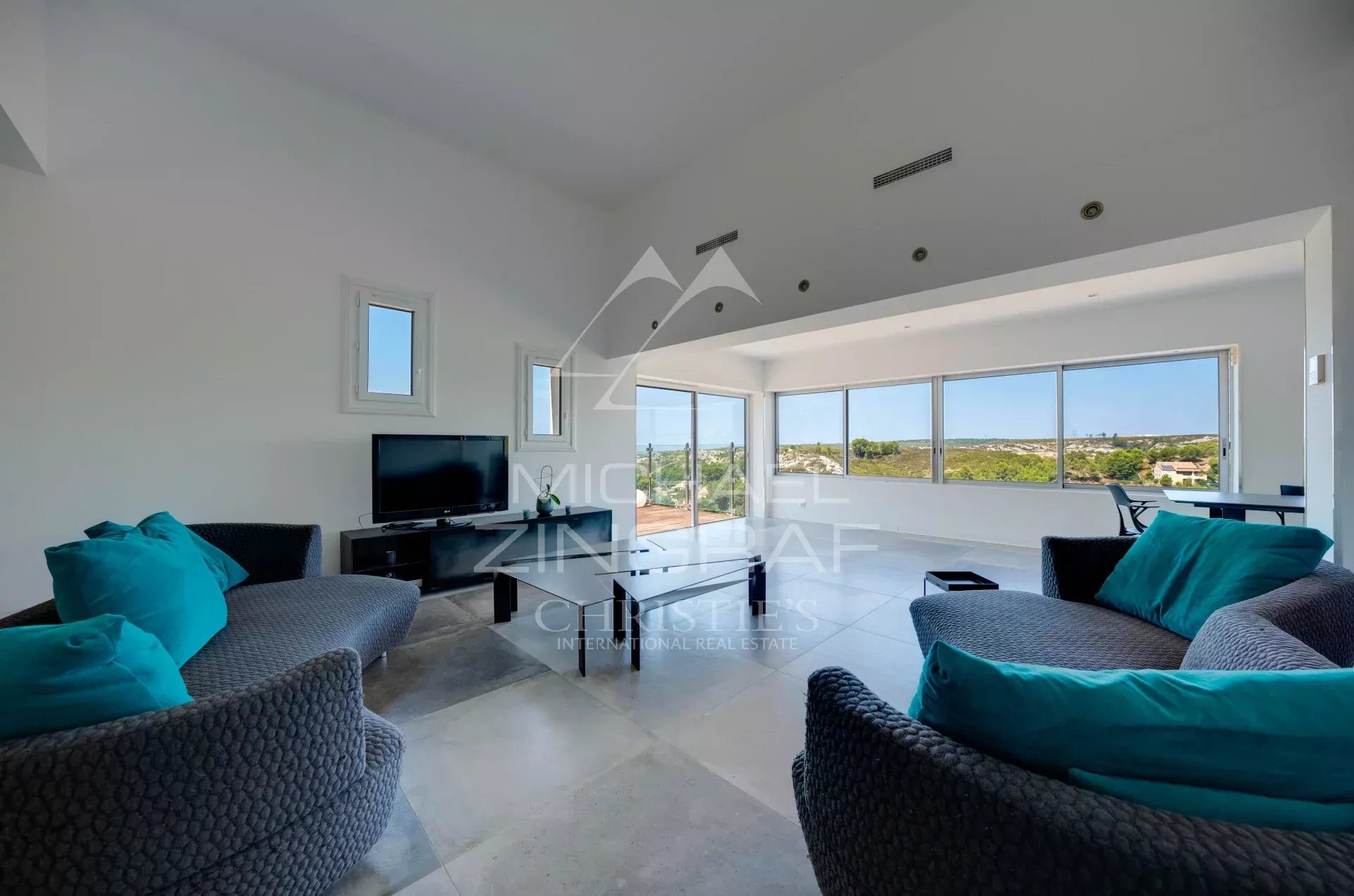 Intérieur d'une villa moderne avec vue sur la mer, salon lumineux et mobilier contemporain.