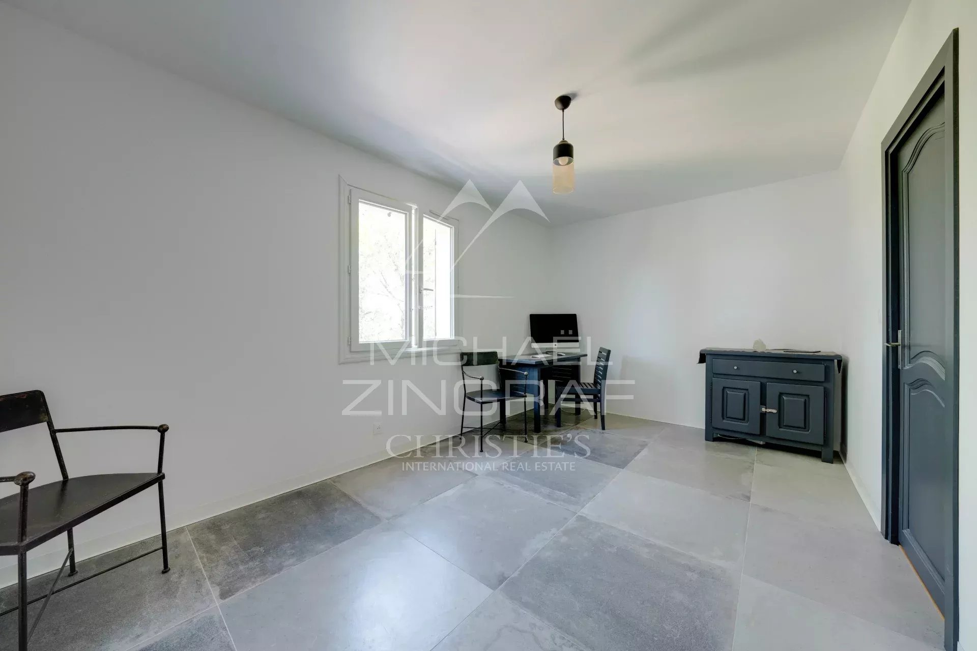 Intérieur d'une villa à Ensuès-la-Redonne, pièce lumineuse avec fenêtres et mobilier minimaliste.