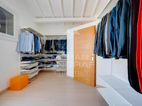 Intérieur d'un dressing bien organisé avec vêtements sur cintres et étagères.