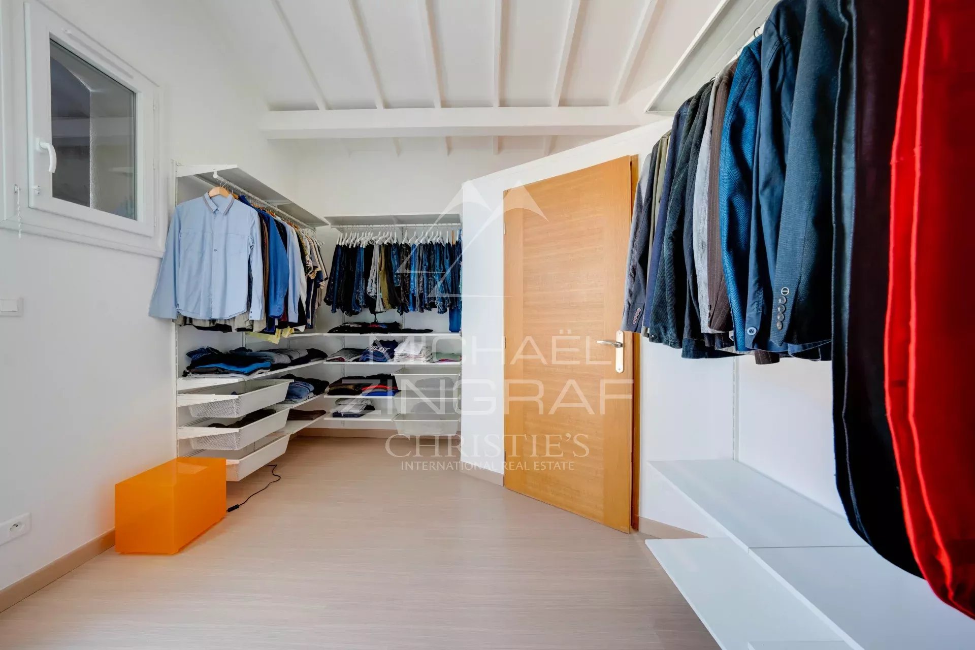 Intérieur d'un dressing bien organisé avec vêtements sur cintres et étagères.