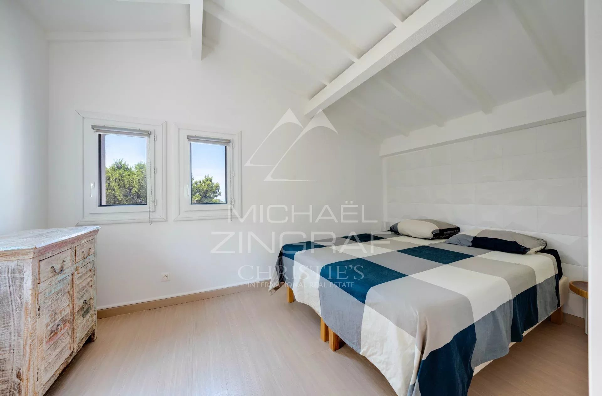 Chambre d'une villa à Ensuès-la-Redonne avec deux fenêtres et un lit double.