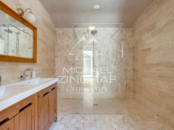 Spacious bathroom with walk-in shower and wooden vanity, marble decoration.