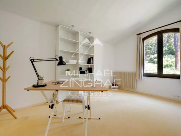 Interior of a 1970s house with an office and a window overlooking a park.