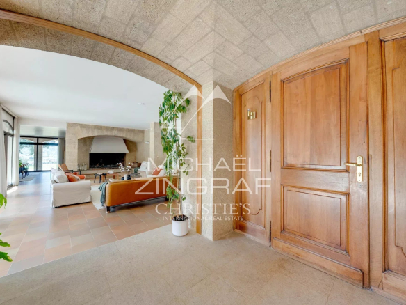 Interior of a 1970s house with stone walls and wooden doors, bright living room.
