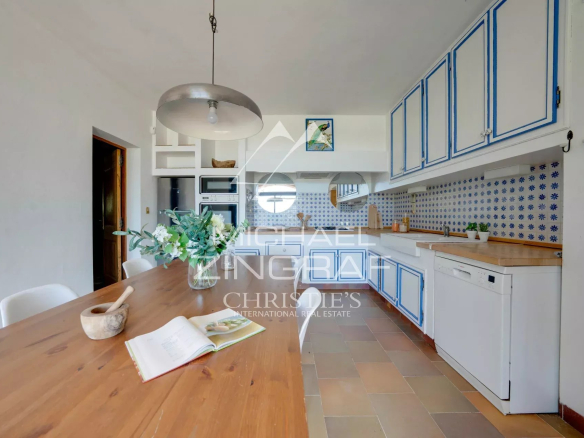 Spacious kitchen with white furniture and blue tiles, abundant natural light.