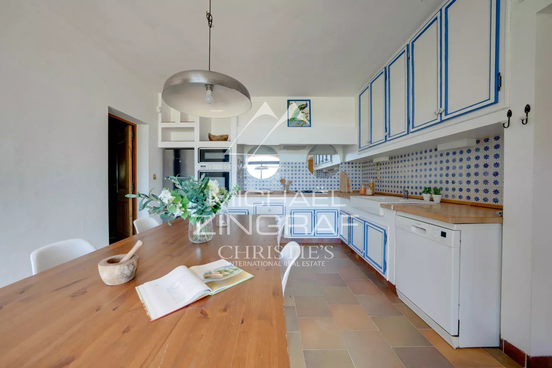Kitchen of a 1970s house Spacious kitchen with white furniture and blue tiles, abundant natural light.