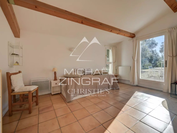 Intérieur lumineux d'une maison avec carrelage et accès à l'extérieur, entourée de nature.
