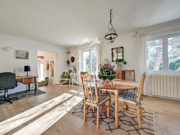Intérieur lumineux d'une maison avec salle à manger et salon, fenêtres ouvertes sur la nature.