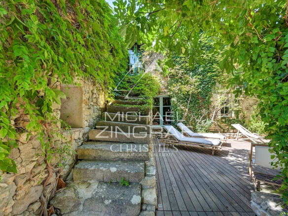 Stone steps leading to a terrace with sun loungers, surrounded by greenery