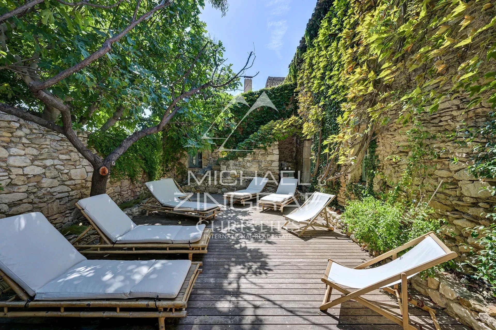 Terrace of a renovated silkworm farm Wooden terrace with sun loungers and stone walls covered in greenery in a renovated property.
