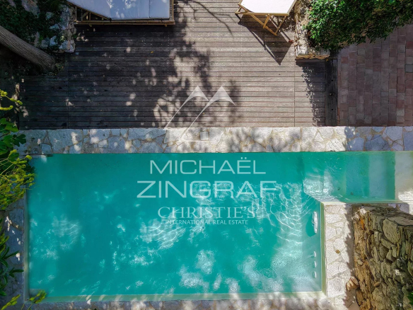 Aerial view of a swimming pool in a renovated property with a wooden area around it.