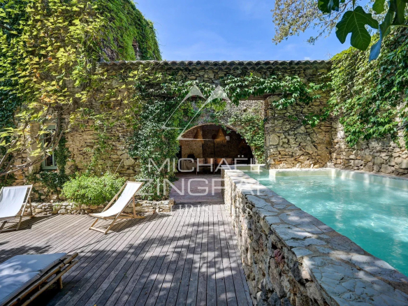 Swimming pool surrounded by stone walls and greenery in a renovated property in La Fare-les-Oliviers.