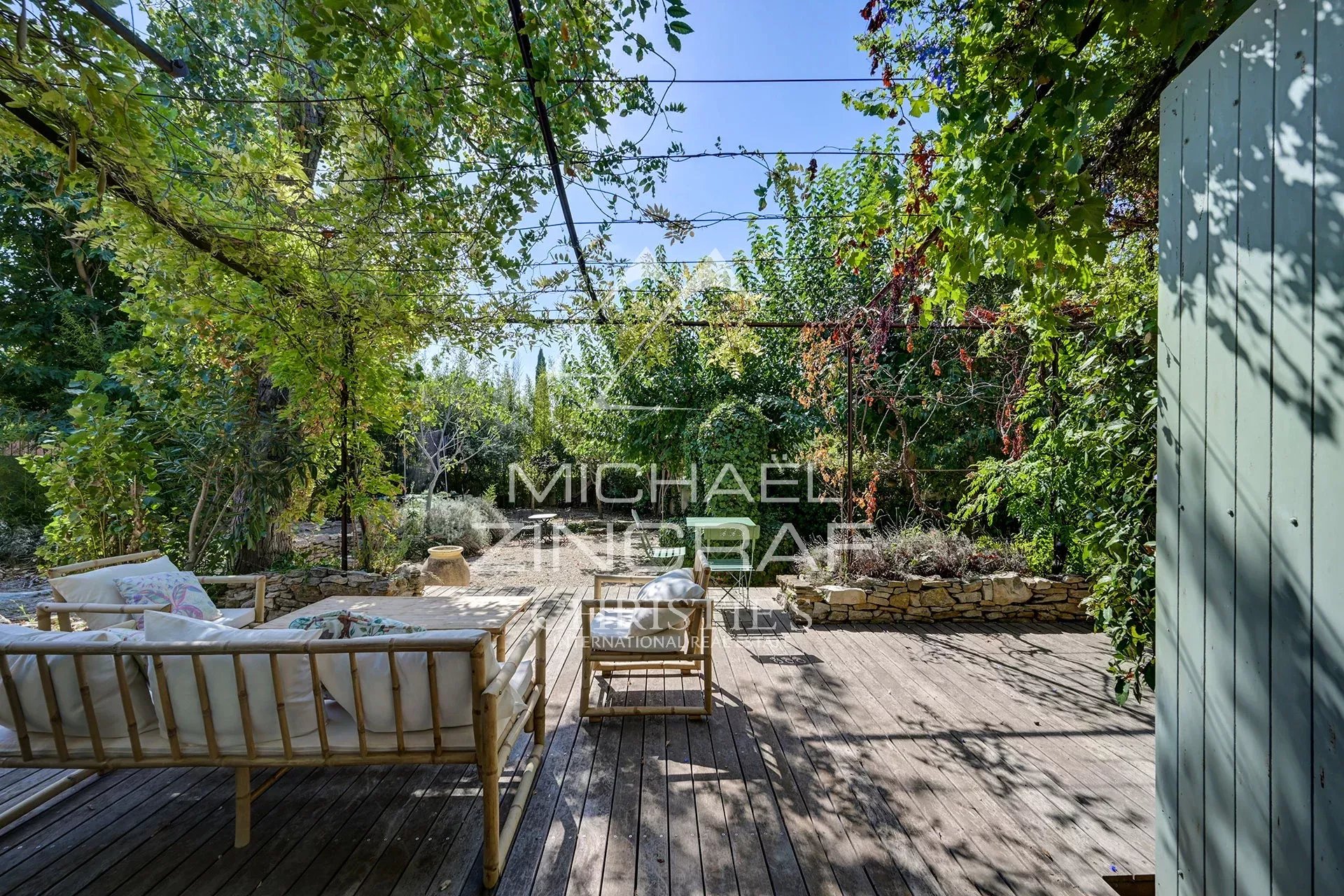 Terrace of the renovated Magnanerie Wooden terrace with garden furniture in a green space