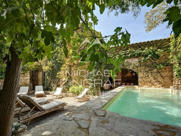 Swimming pool surrounded by greenery and ancient stones in a renovated silkworm farm.