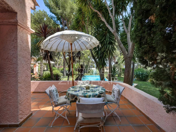 Terrace of a villa in La Ciotat with table and parasol, overlooking the garden and swimming pool.