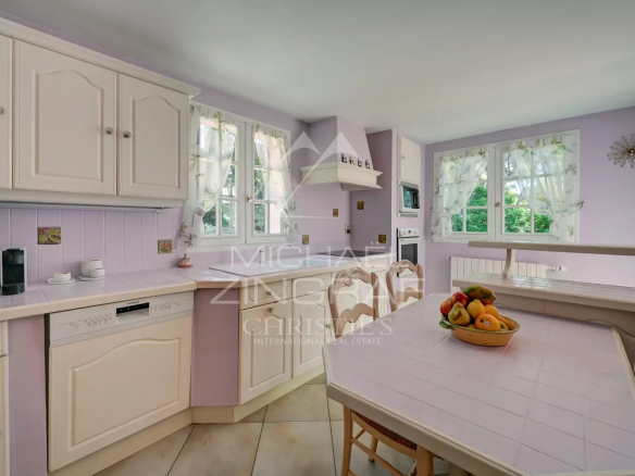 Bright kitchen in a villa in La Ciotat, with white furniture and lilac walls.