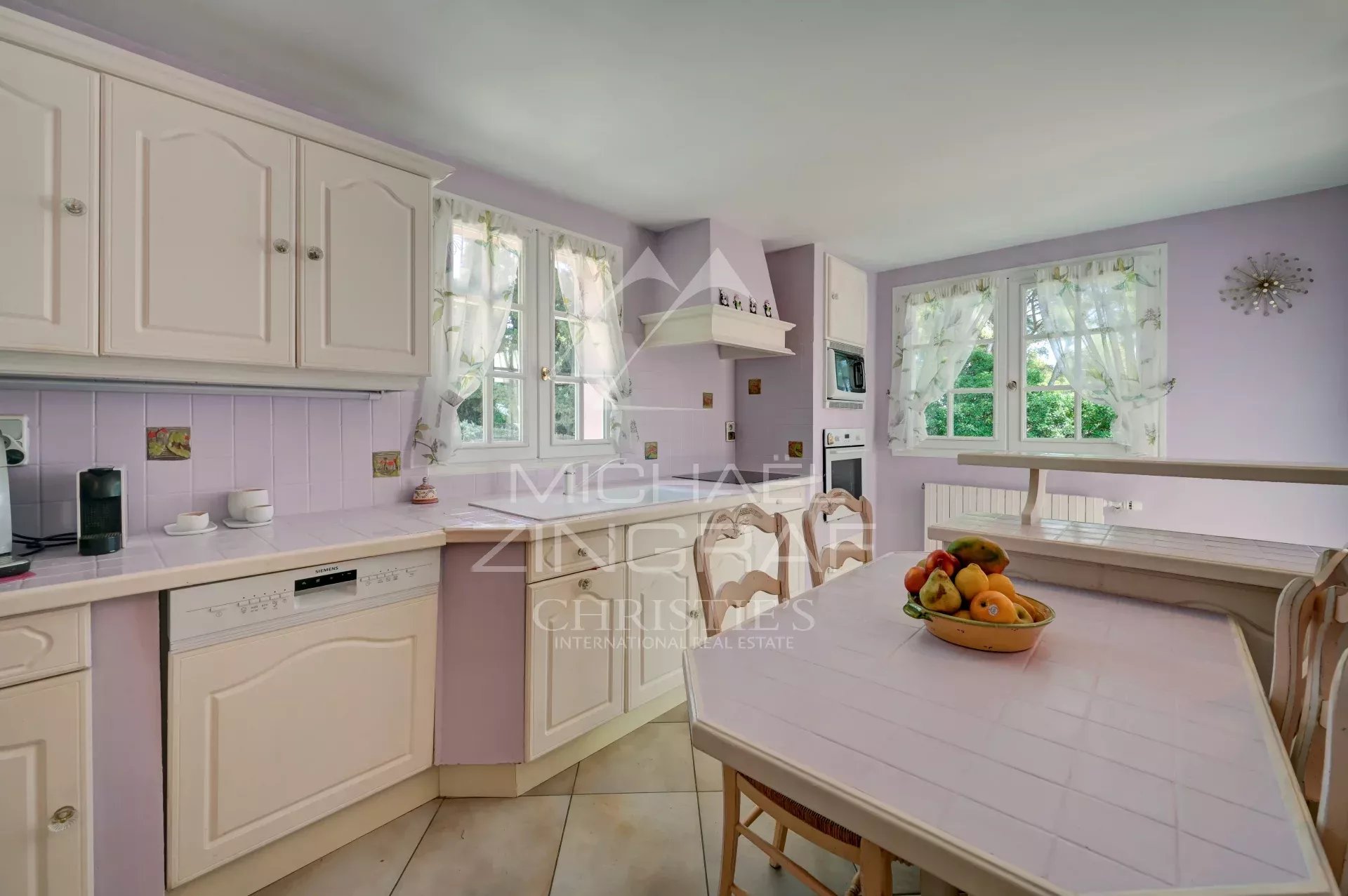 Kitchen of a villa in La Ciotat Bright kitchen in a villa in La Ciotat, with white furniture and lilac walls.