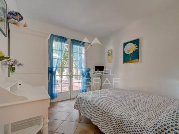 Bright room with a single bed and windows draped with blue curtains.