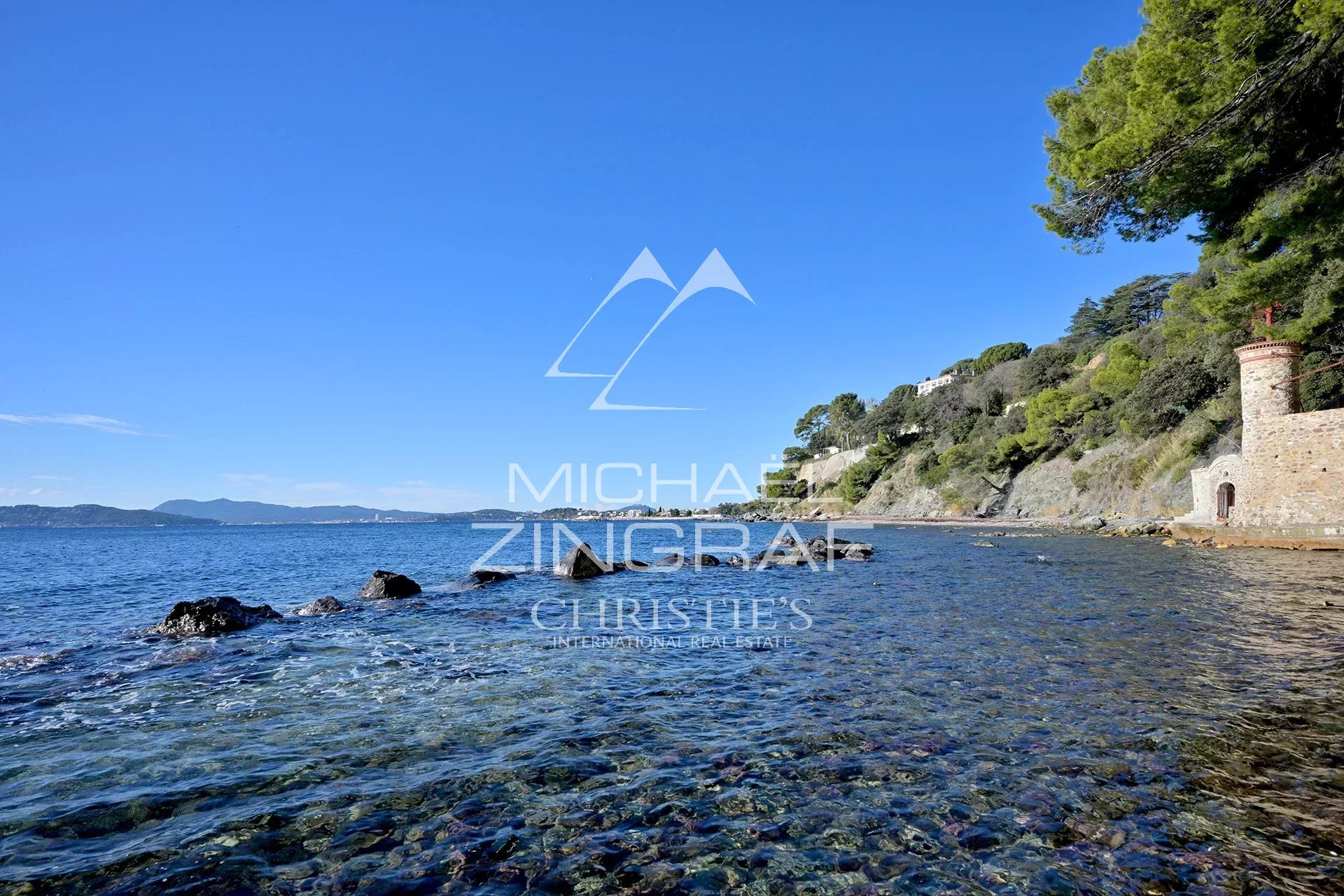 View of the sea and rocks at Cap Brun, Toulon, with trees in the background.