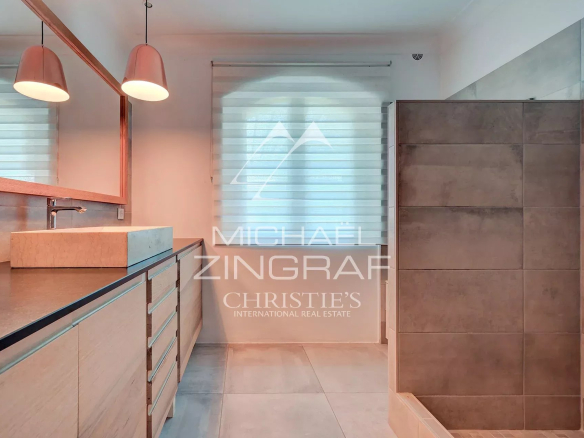 Salle de bain moderne avec douche et meuble en bois, lumière naturelle à travers la fenêtre.