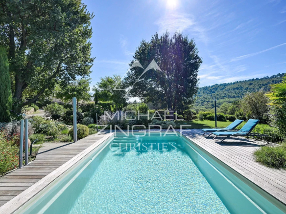 Piscine d'une propriété paysagée à Ansouis, entourée de verdure et de collines.