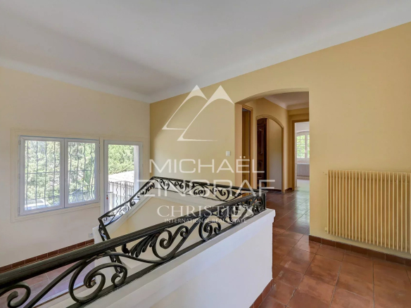 Intérieur d'une bastide avec un escalier et des fenêtres donnant sur un parc.