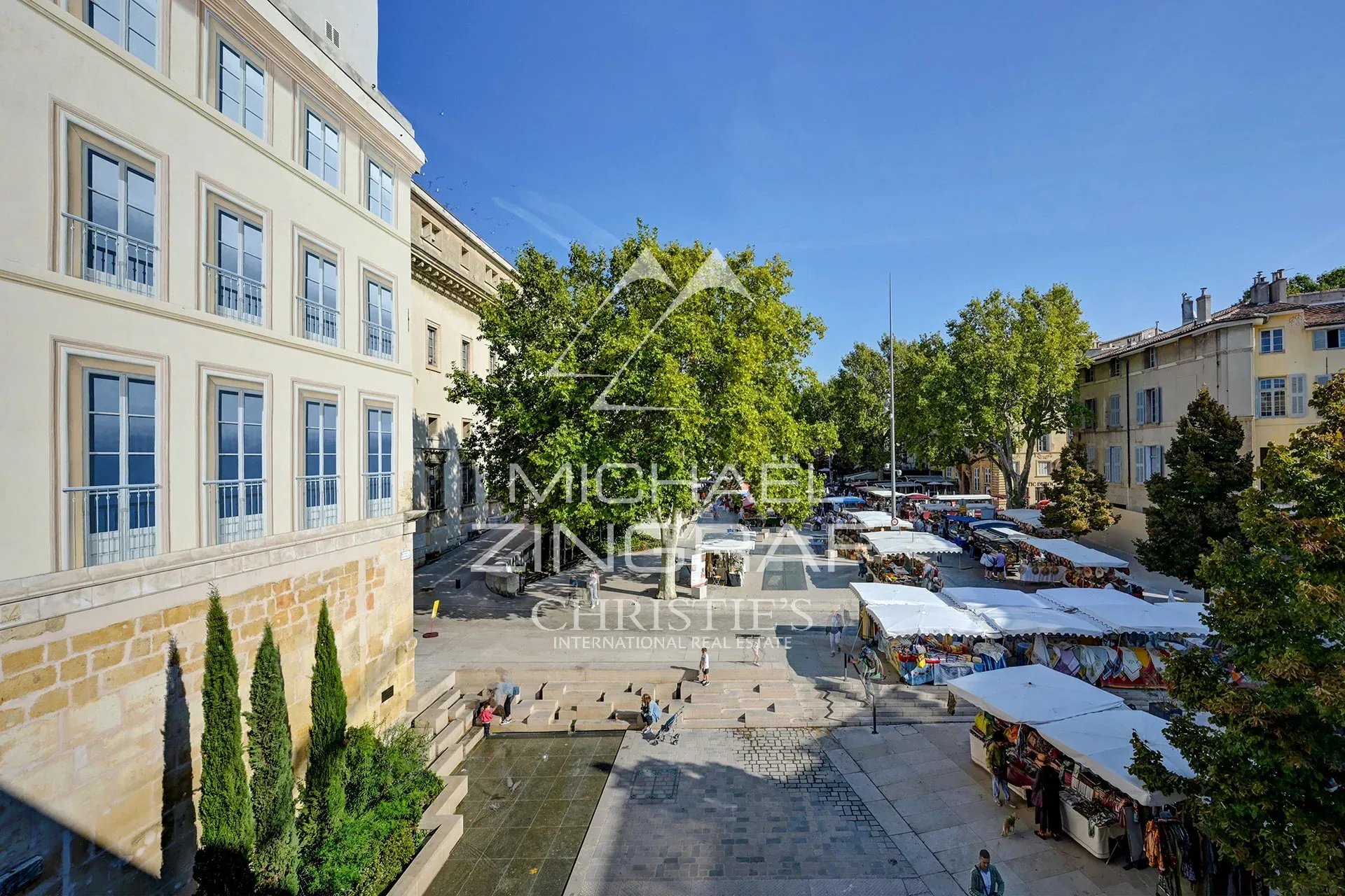 Vue de la place des Prêcheurs à Aix-en-Provence avec un marché traditionnel et des bâtiments historiques.