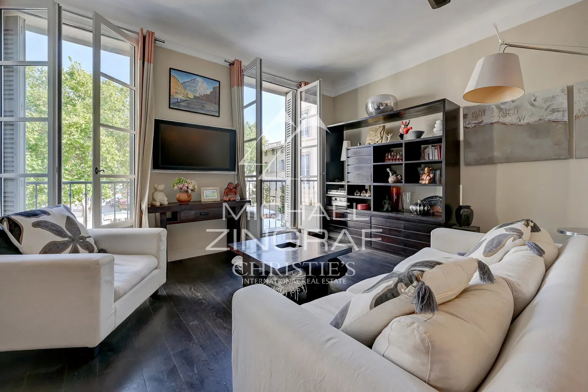 Salon lumineux d'un appartement d'exception à Aix-en-Provence avec fenêtres sur la place des Prêcheurs.