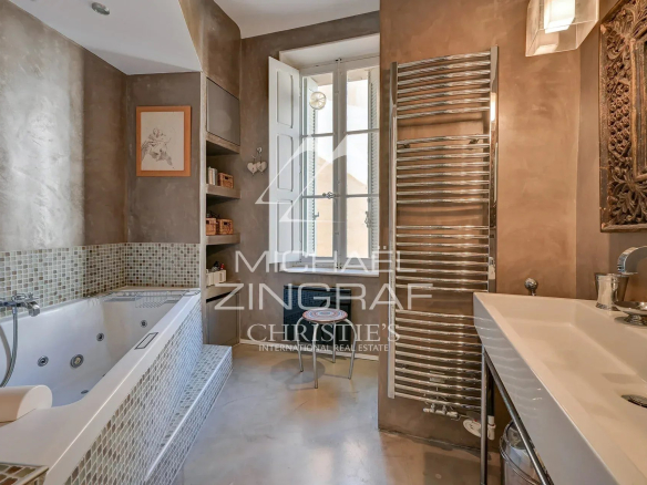 Salle de bain moderne avec baignoire et lavabo, murs en béton et décoration élégante.