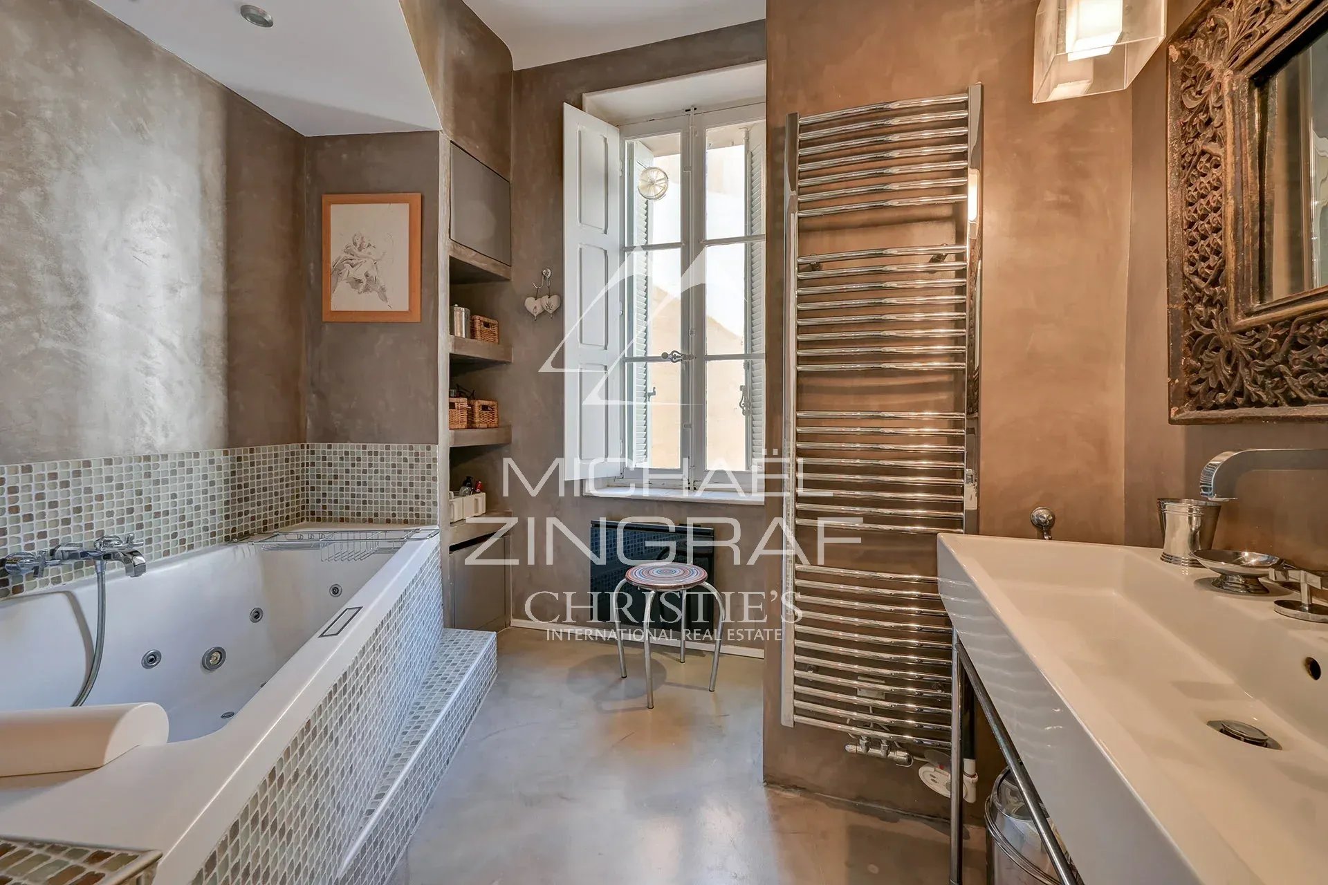 Salle de bain moderne avec baignoire et lavabo, murs en béton et décoration élégante.