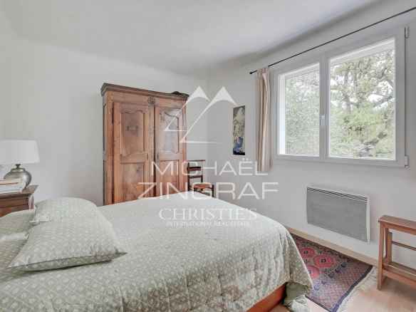 Chambre d'une maison d'architecte à Aubagne avec un lit et un meuble en bois.