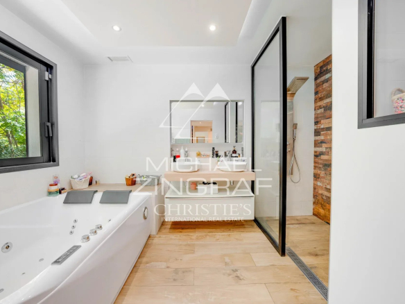 Salle de bain moderne avec baignoire et douche, fenêtres donnant sur la nature.