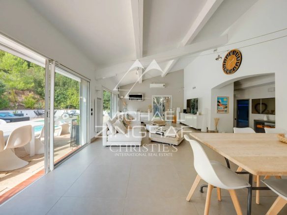 Intérieur d'une maison moderne avec une salle à manger lumineuse et vue sur une piscine extérieure.