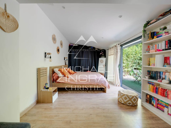 Intérieur d'une maison avec lit, bibliothèque et accès à un jardin.