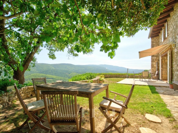 Wooden terrace with table and chairs, overlooking the green valley at Montjustin.