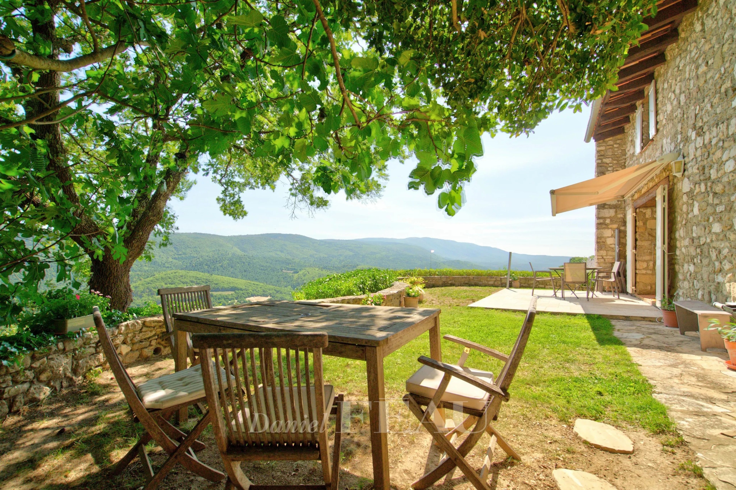 Wooden terrace with table and chairs, overlooking the green valley at Montjustin.