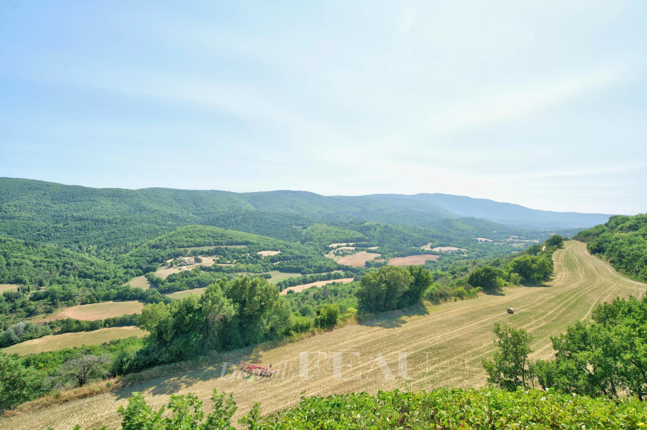 Panoramic view of the hills and fields around Montjustin, with a clear sky.