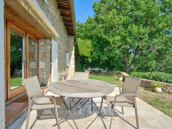 Stone terrace with round table and chairs, overlooking the green countryside in Montjustin.