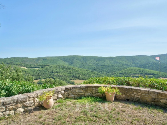 Panoramic view of green hills from a stone terrace.
