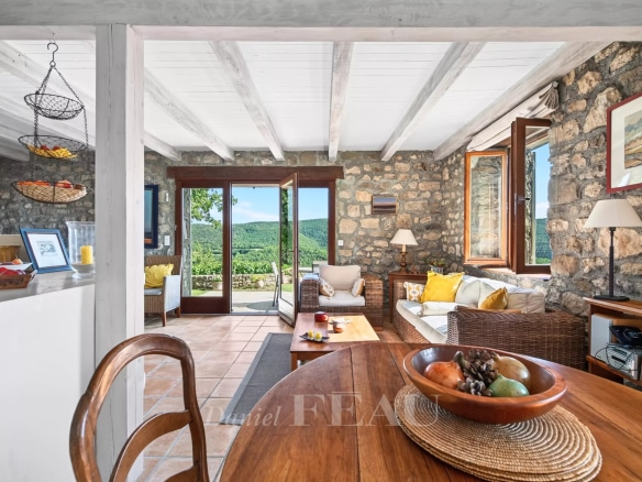 Interior of a stone house with views of nature, bright living room and open kitchen.