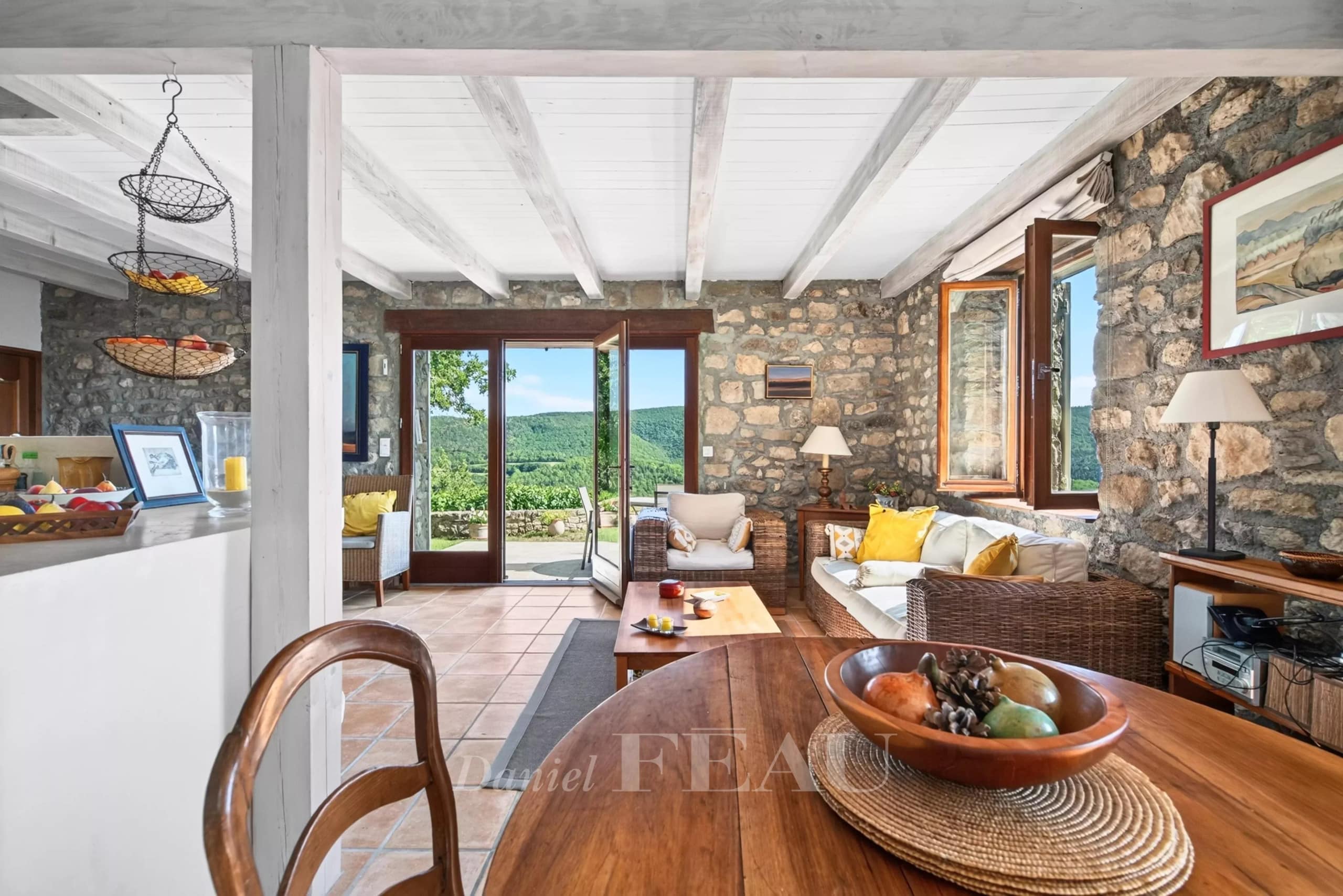 Interior of a stone house with views of nature, bright living room and open kitchen.